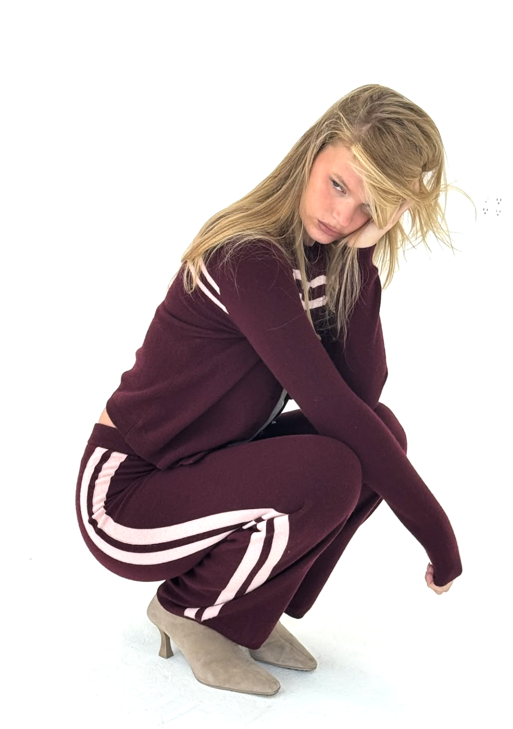 Woman wearing a maroon tracksuit with white stripes on a white background